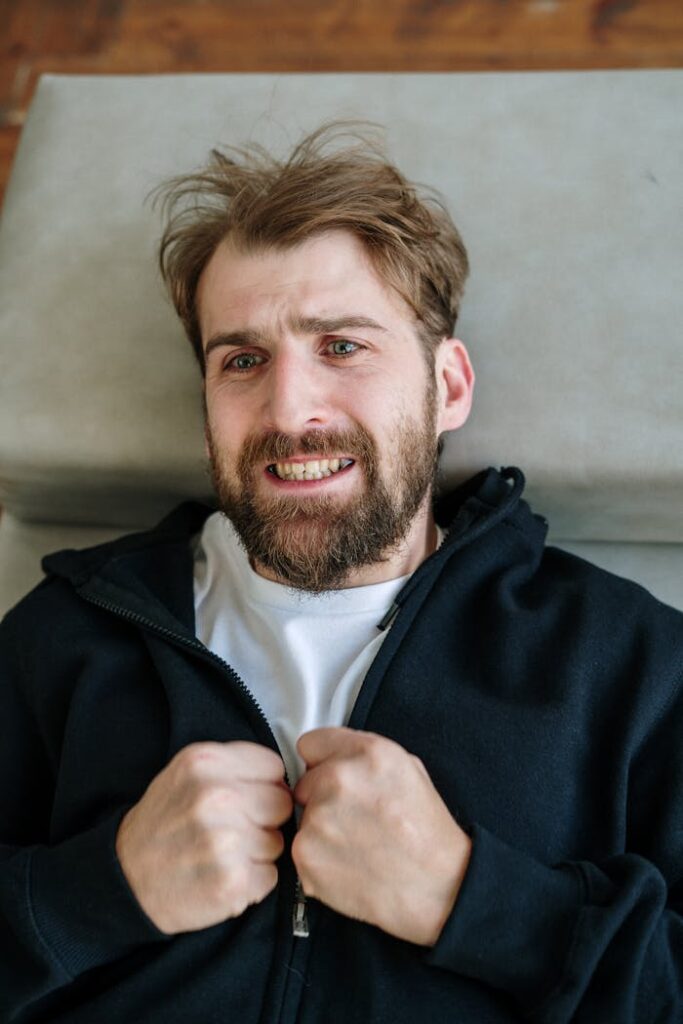 A distressed man lying down, expressing emotion in a therapy setting.